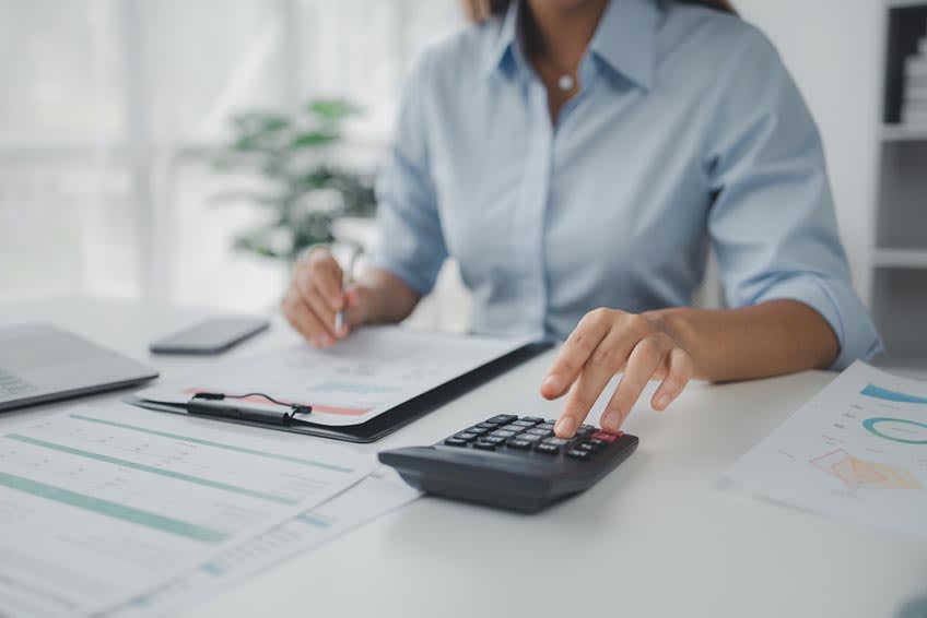 Accounts receivable clerk using calculator to evaluate outsourcing costs
