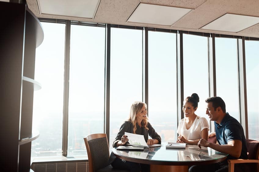 Advisor working with clients in wealth management building holding a report about outsourcing pros & cons