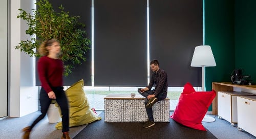 man sitting and woman walking in an office space