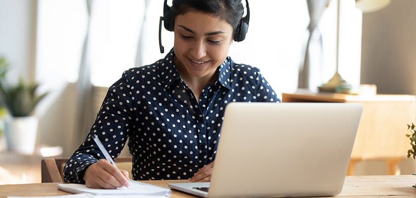 Person watching a webinar on her laptop smiling