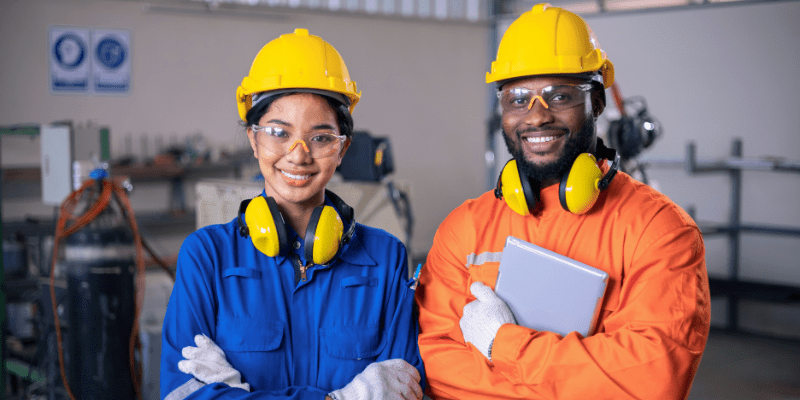 Two workers standing with arms crossed in factory.