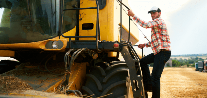 Harvester machine driver climbing into a cab to harvest his wheat field. 