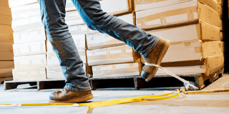 A warehouse worker about to trip on boxes left on the floor.