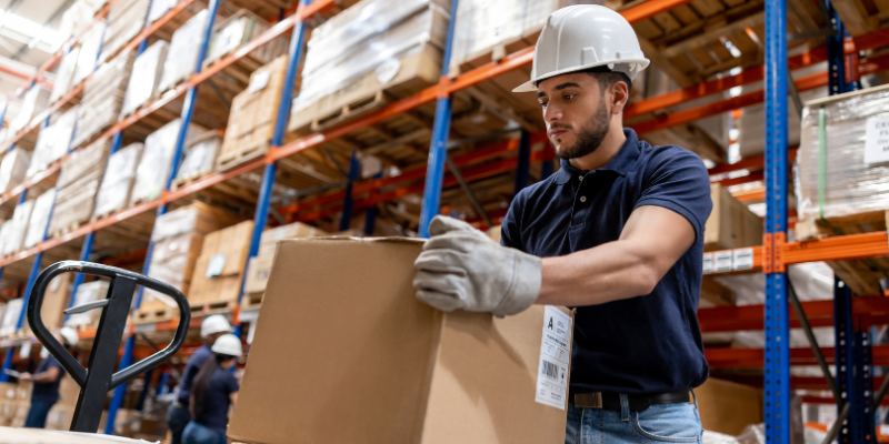 Worker lifting a box in a warehouse.