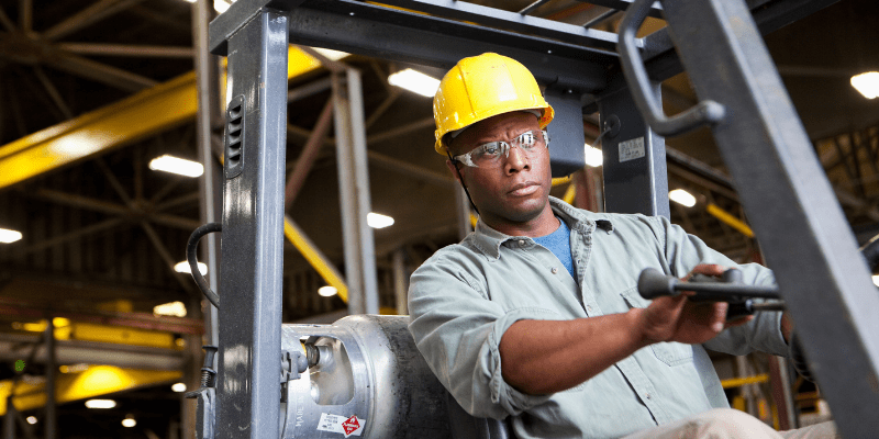 Worker on a forklift wearing a yellow hardhat.