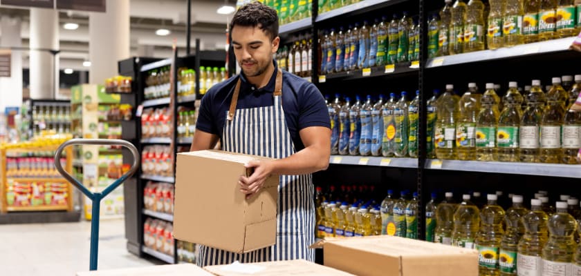 Grocery clerk working at the supermarket restocking the shelves.