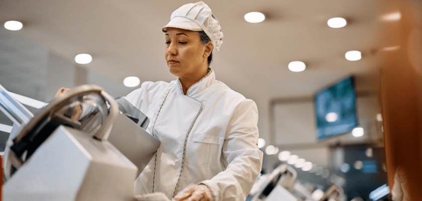Supermarket worker using a slicer at delicatessen section.