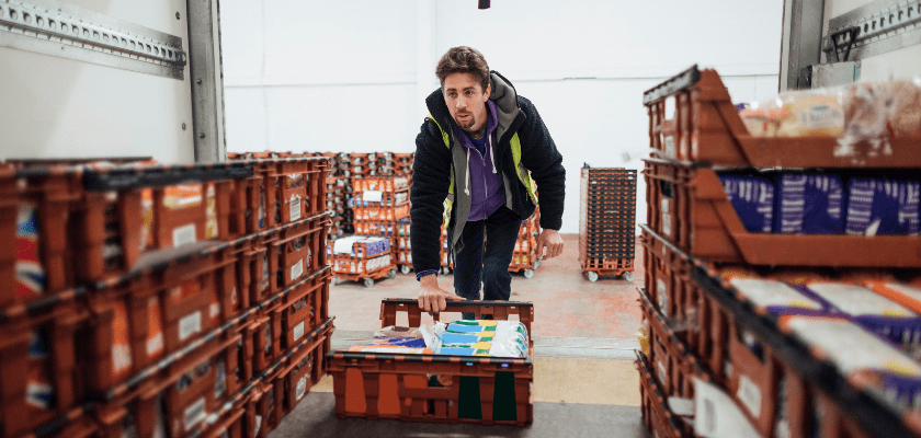 Grocery store worker unloading a trailer of products.