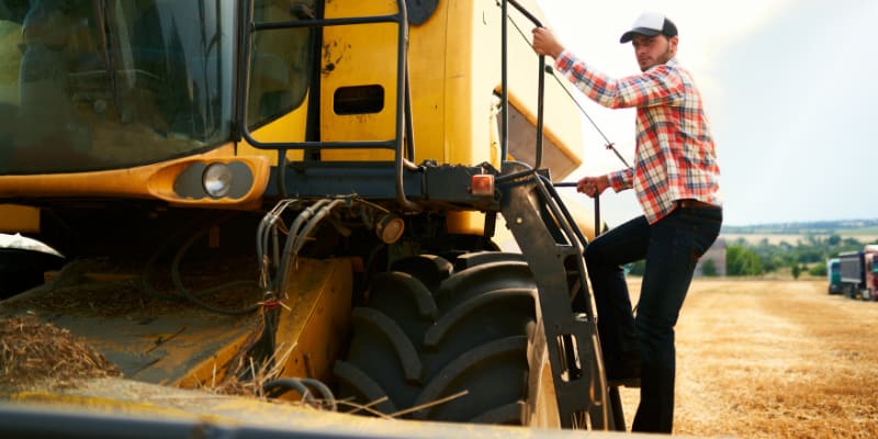 Ag worker climbing onto a tractor.