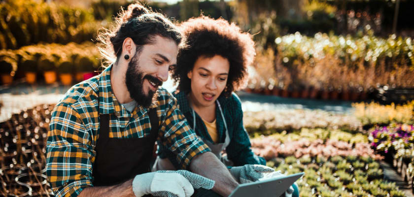 Two landscapers looking at a tablet in a garden.