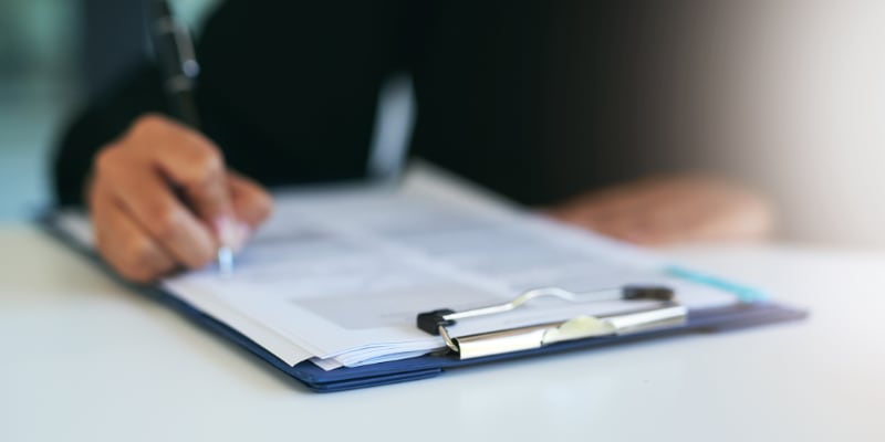 A worker filling out a form on a clipboard.