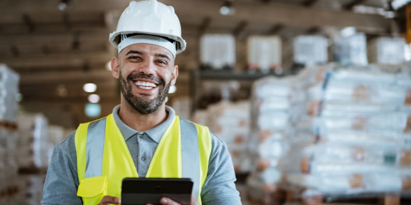 Worker holding a clipboard with a hardhat on.