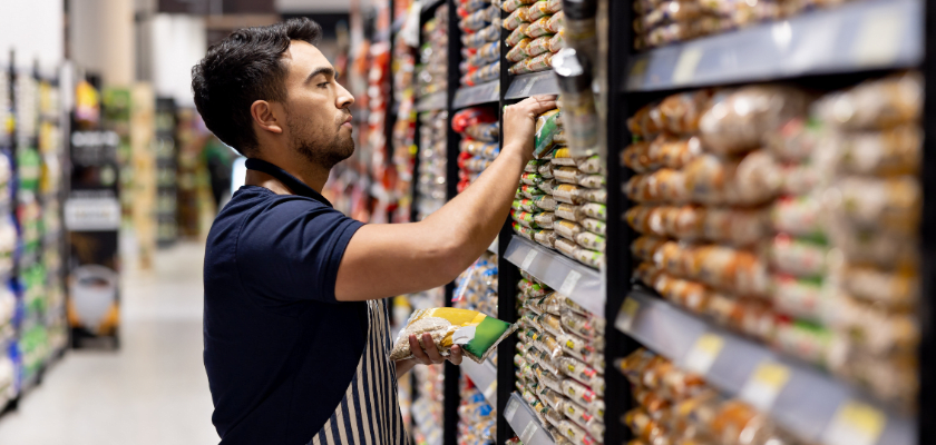 Retail clerk working at the supermarket restocking the shelves.