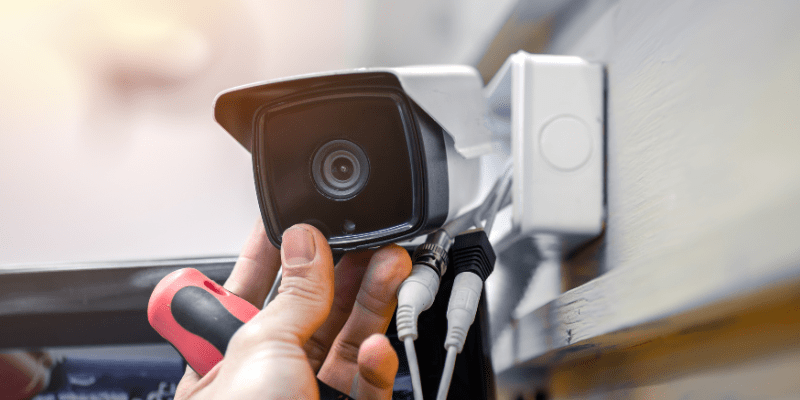 Close-up of surveillance camera installation, male hand holds cctv camera
