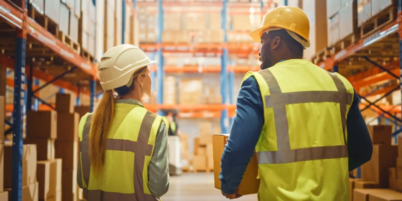 Two warehouse workers walking in the workplace.
