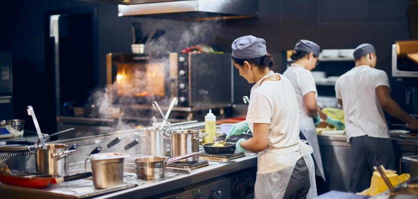 A team of cooks backs in the work in a modern kitchen, the workflow of the restaurant in the kitchen.