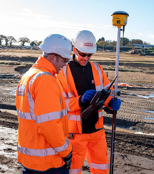 Two surveyors looking at their data collector.