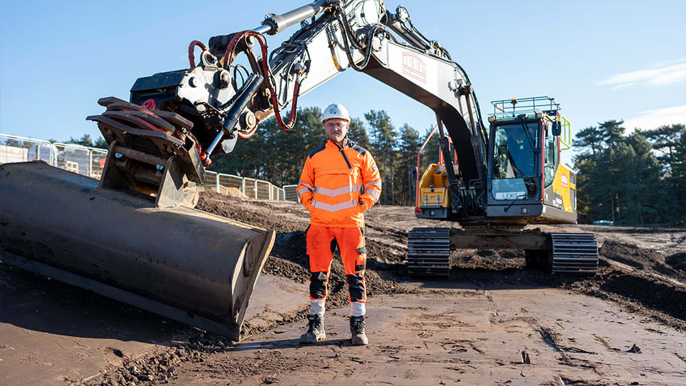 Operator stands in front of excavator