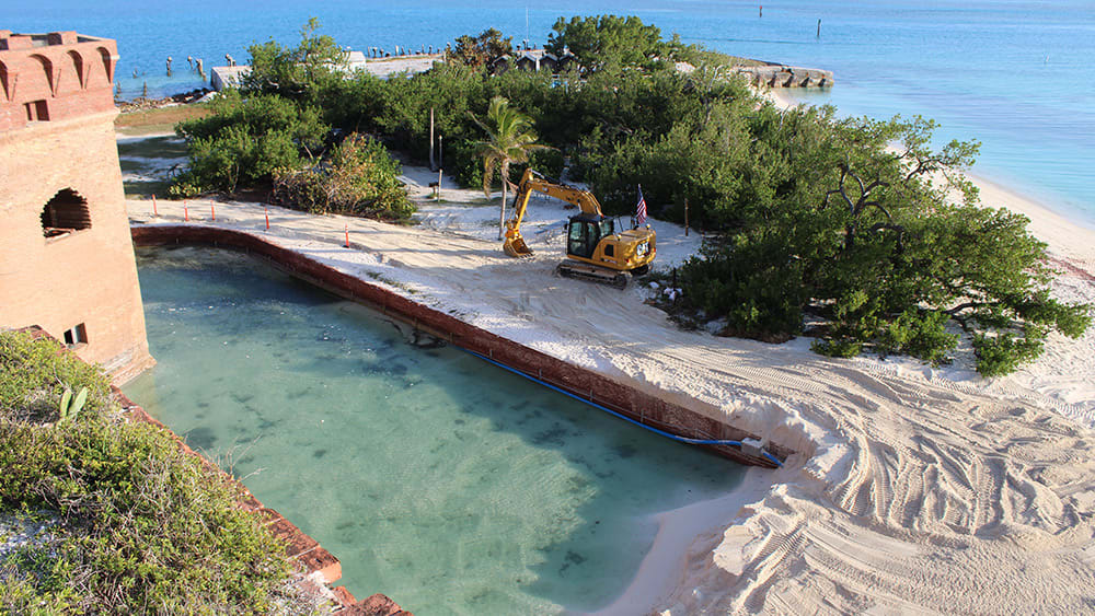 Excavator dredging sand from an old fort