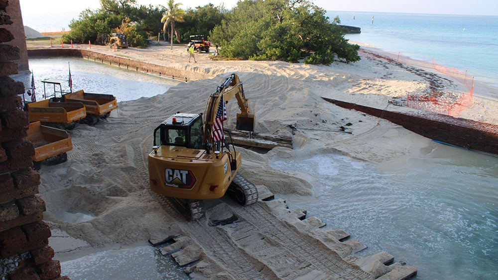 Excavator removing sand from fort moat