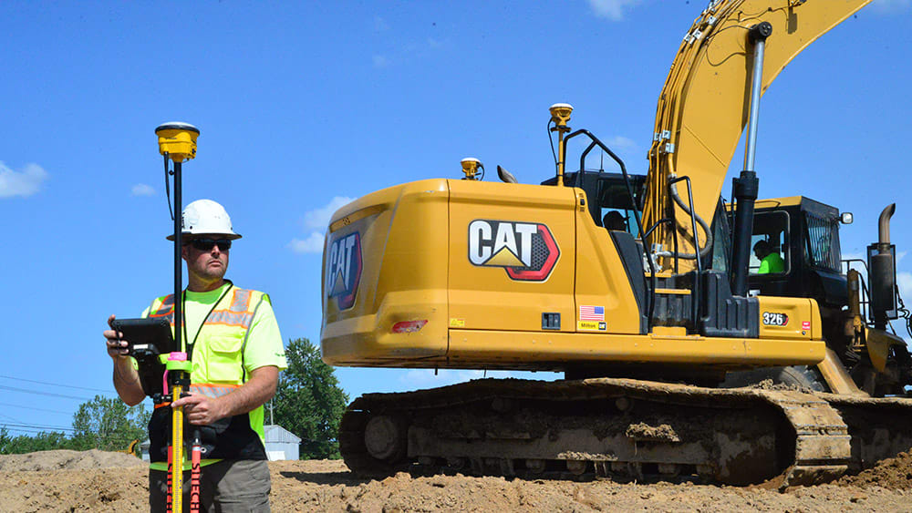 Surveyor in front of excavator with machine control