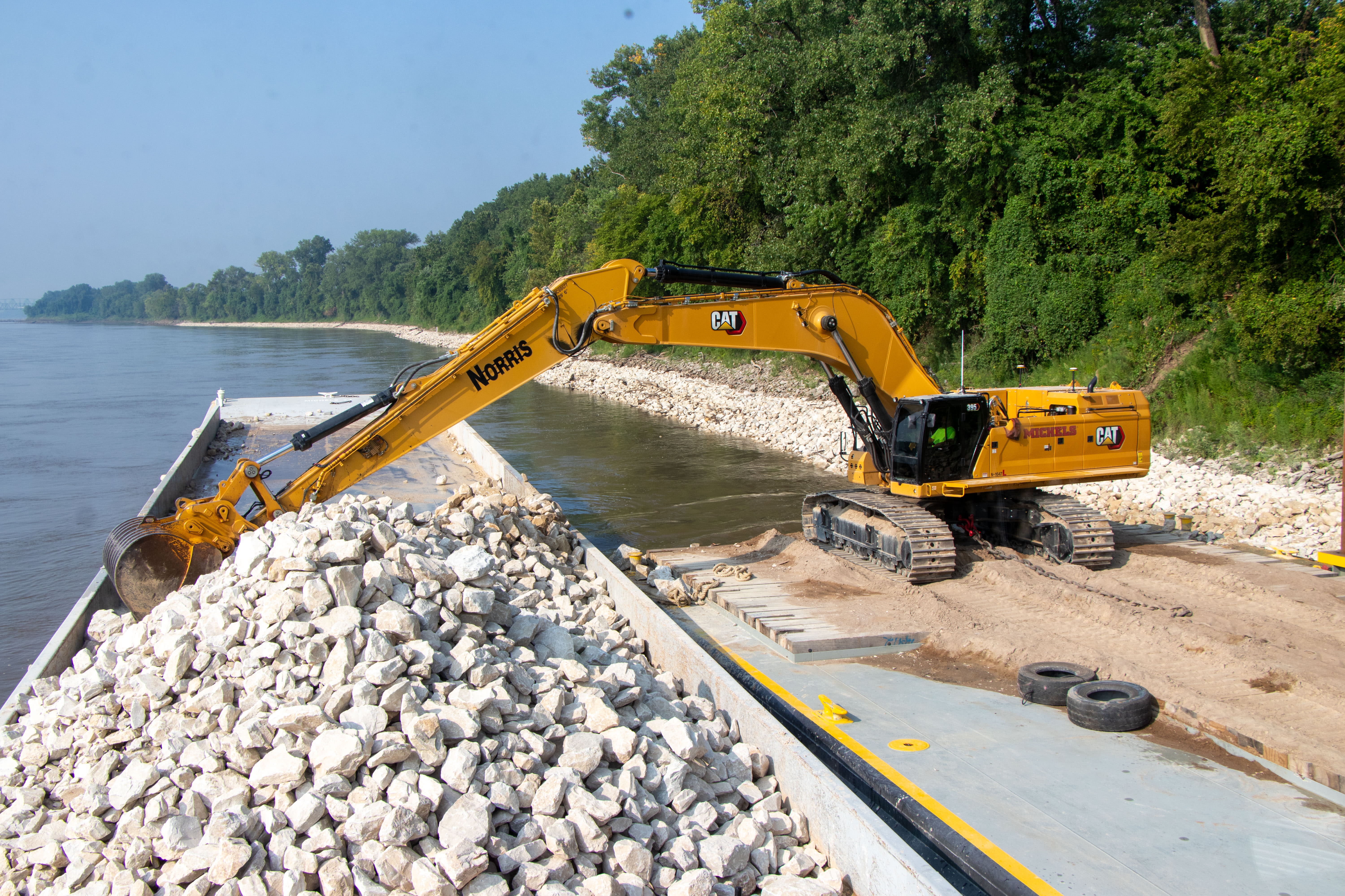 Excavator dumping material into a barge