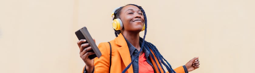 Person listening to music from smartphone using wireless headphones and smiling