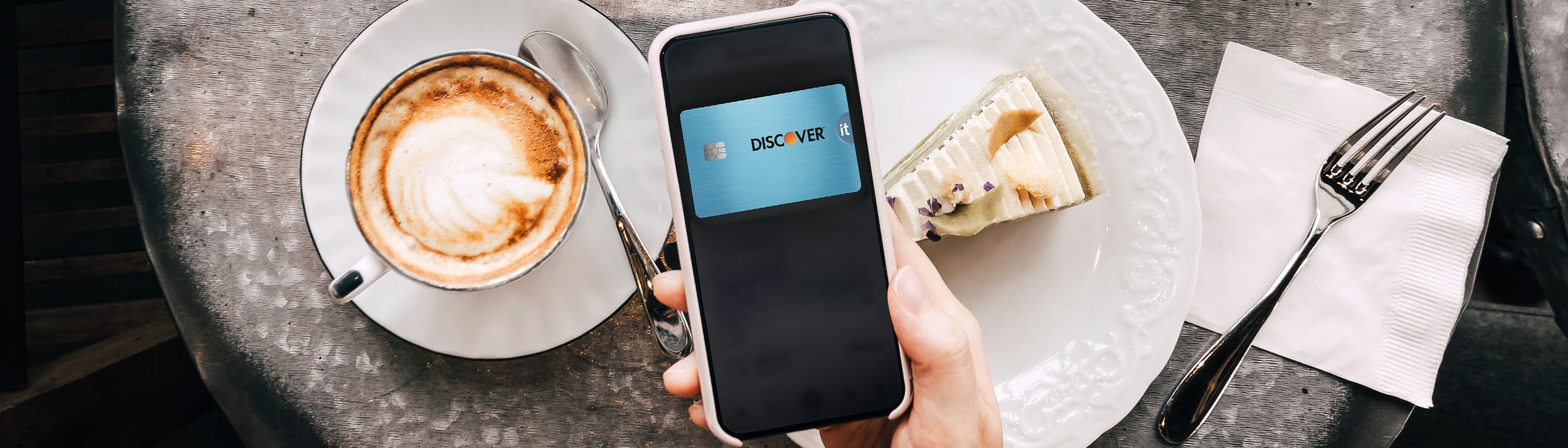 Customer using their discover card on mobile phone to pay for coffee and food
