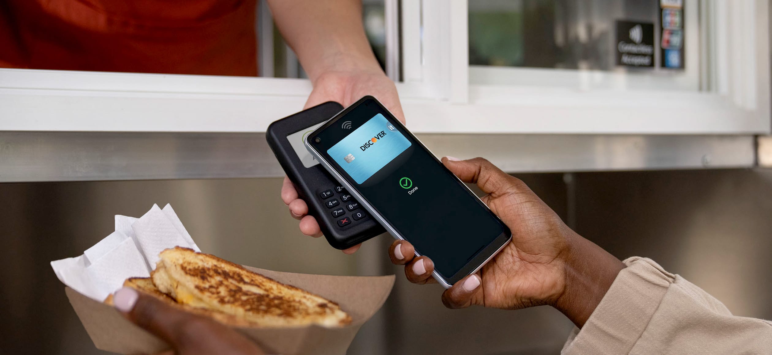 Person using mobile tap to pay transaction to pay for sandwich