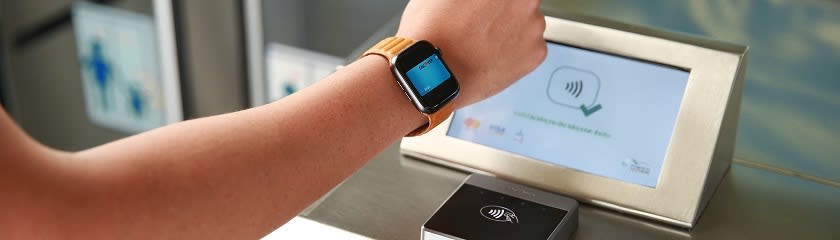 A person paying with a smartwatch at a contactless payment terminal.