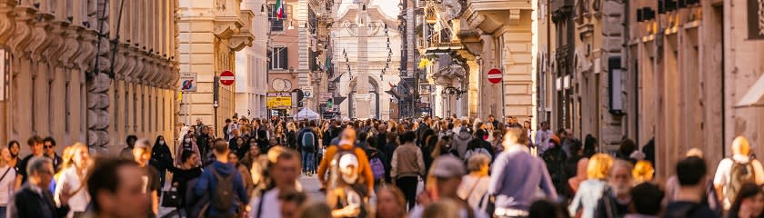 A busy urban street scene with a large crowd of people walking.