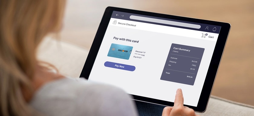 Consumer making a secure online payment with a Discover card on a tablet.