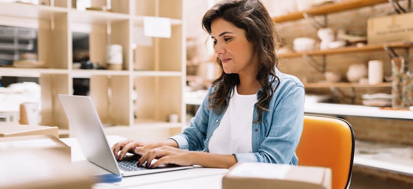 Employee at desk in back of store using laptop