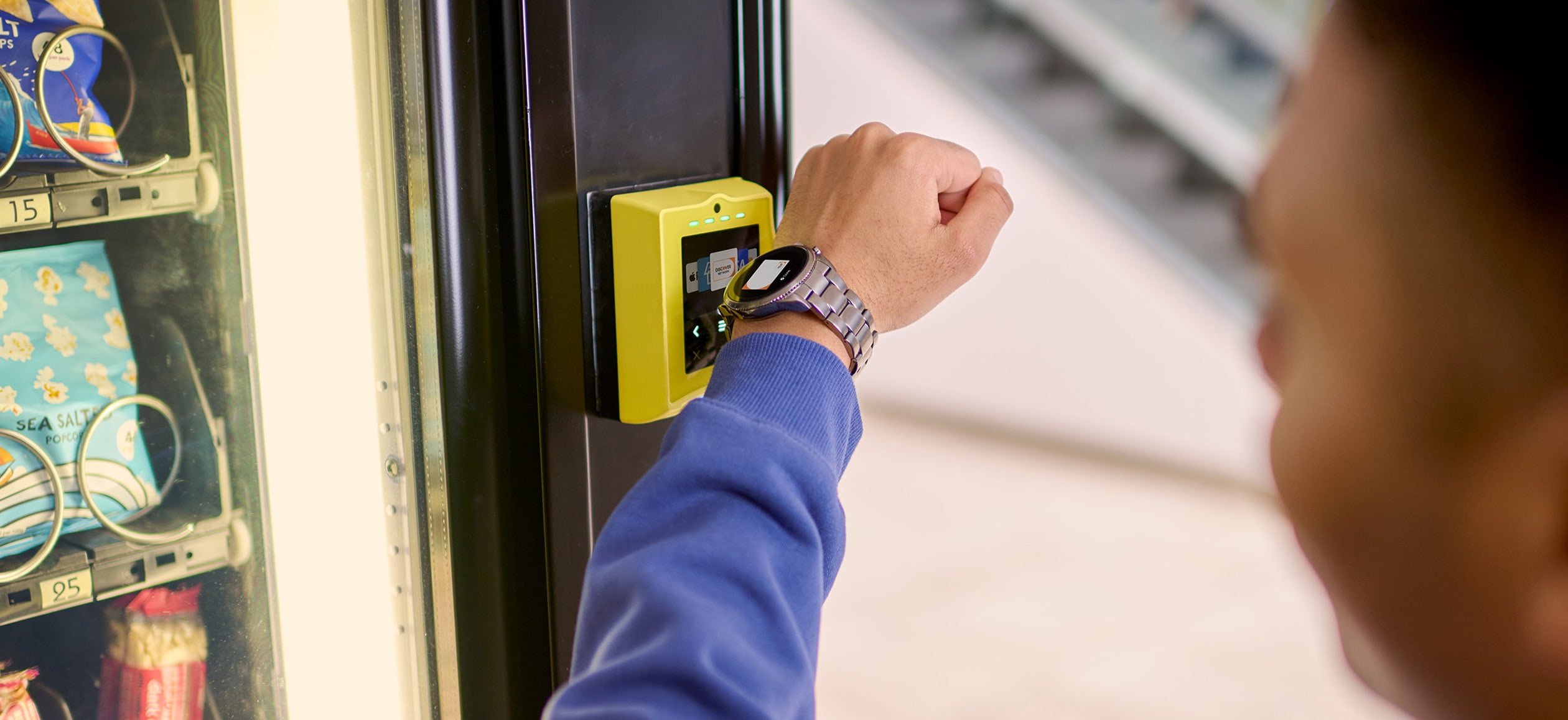 Person making a contactless payment at a vending machine using a smartwatch wearable device.