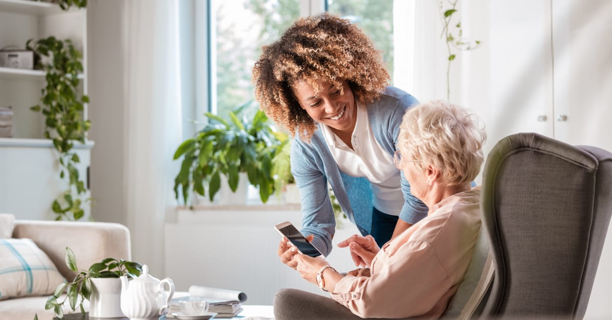 An  elderly person sitting in a chair with a smart phone in front of them