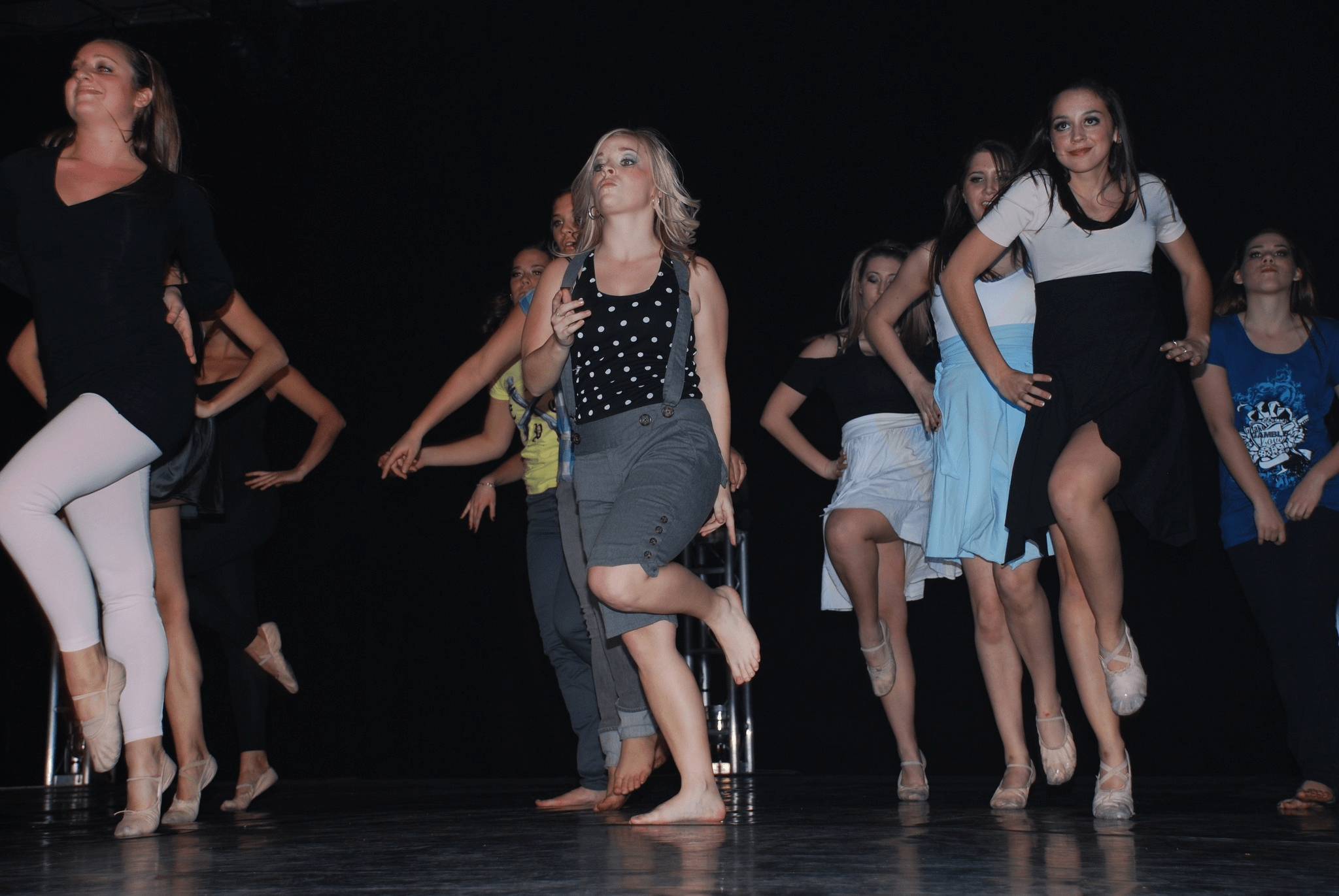 Amanda Richardson dancing on stage with a group of students.