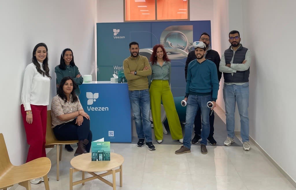 Groupe de huit personnes posant au stand de Veezen avec un équipement de RV