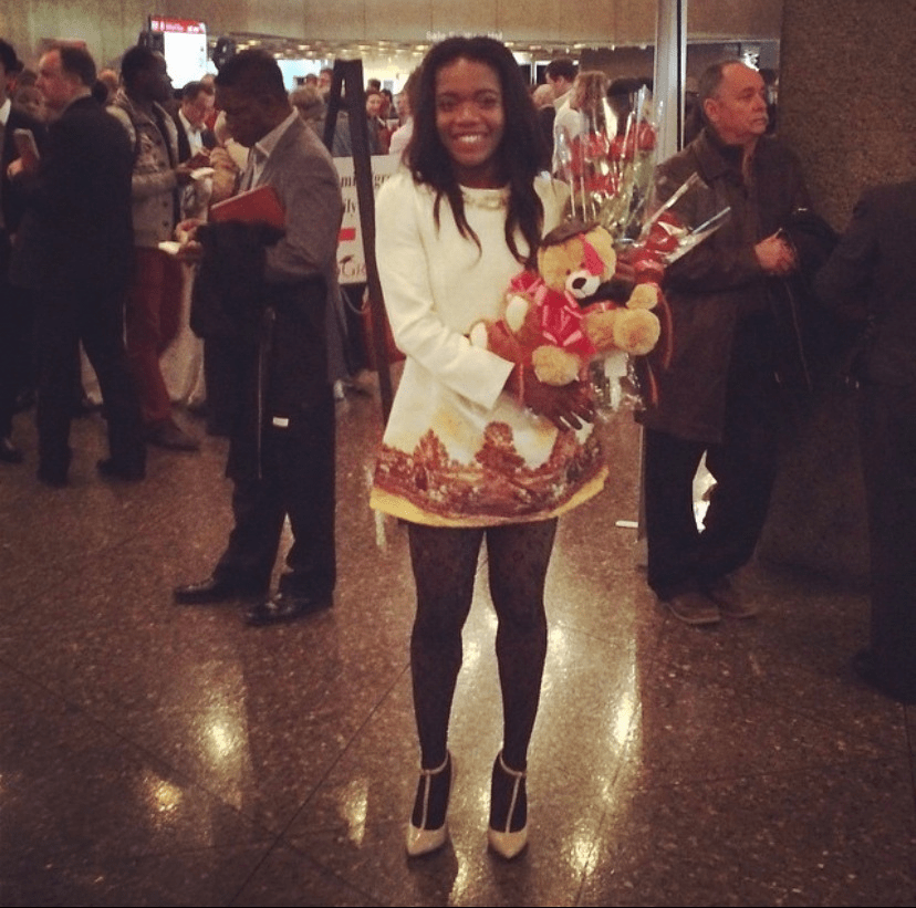 Chizoba holding a bouquet of flowers and a teddy bear.