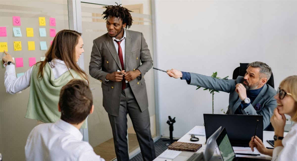 Group of executives working through a problem by going through post-it notes on a board