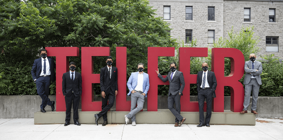 MBA students in masks standing in front of the Telfer sign outside