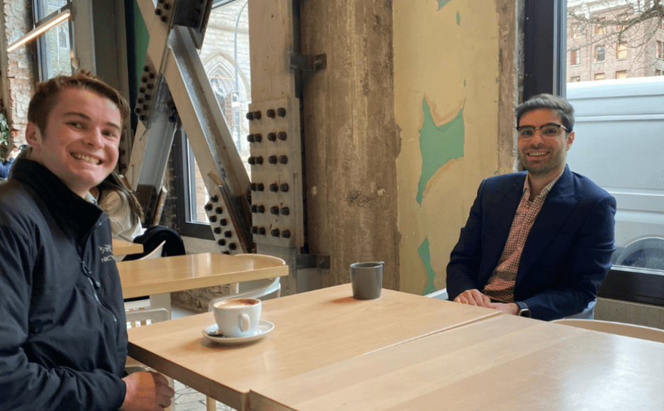 Student and mentor smiling and having coffee.