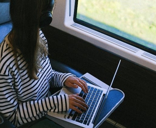 unnamed individual working on a laptop while traveling by train