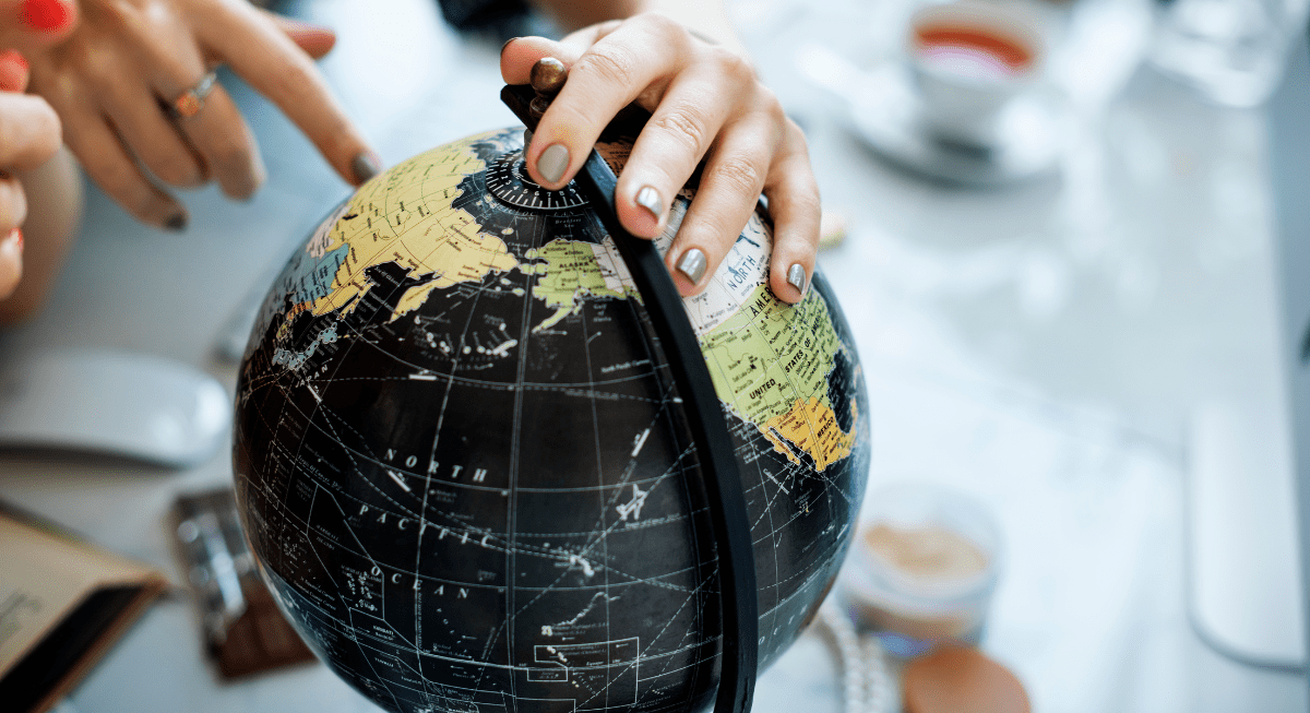 Main tournant un globe dans un espace de travail moderne avec des objets de bureau.