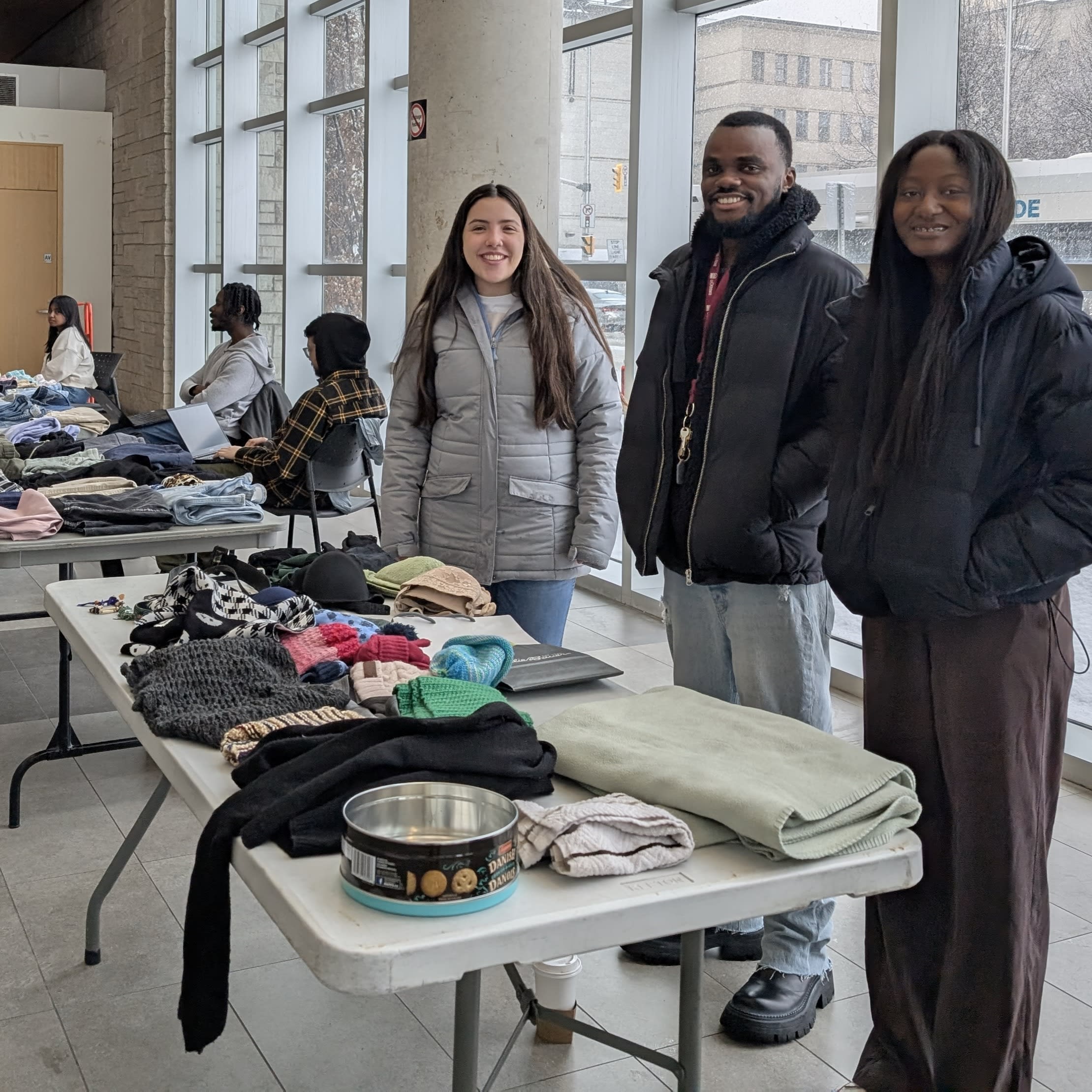 Students stand behind tables laden with items from the Free Store.