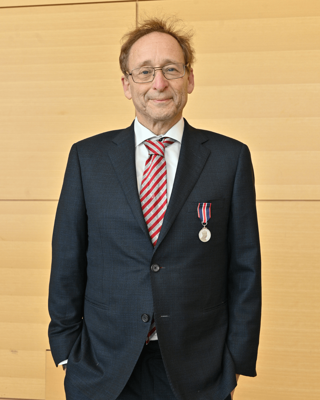 A man in a suit with a small medal pinned to his blazer.