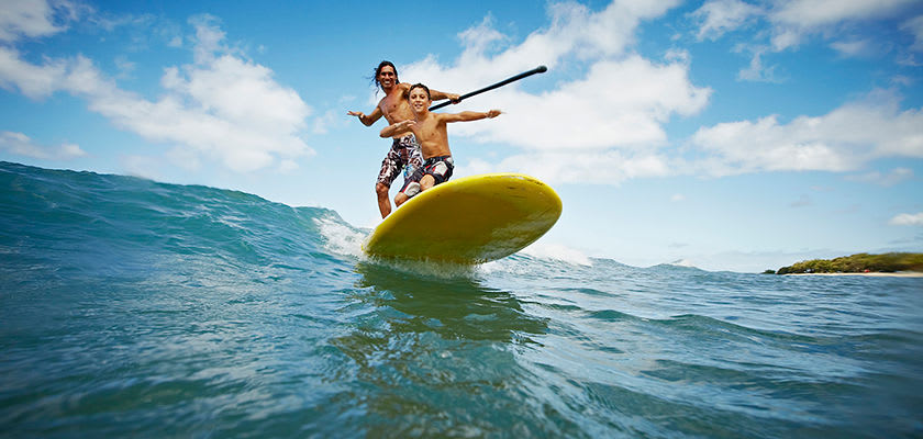 adult and kid surfing on same surfboard