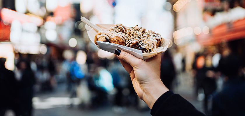 Takoyaki person holding Takoyaki with streets in background