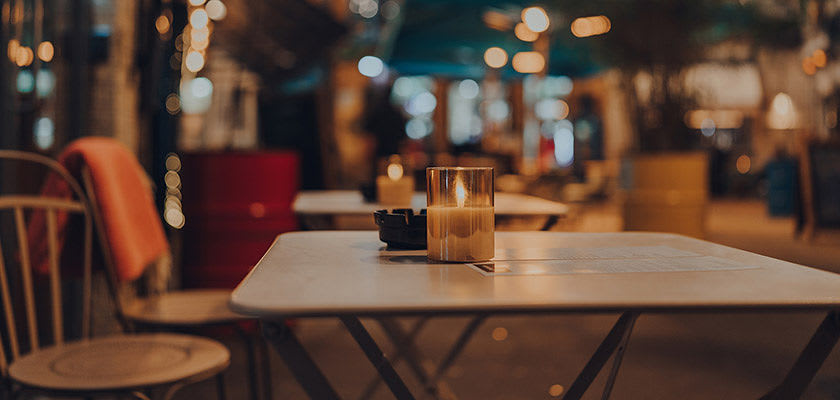 Burning candles on top of outdoor restaurant table at night