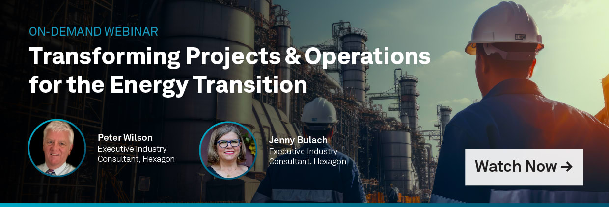 A person in a hardhat walking in front of a factoryDescription automatically generated