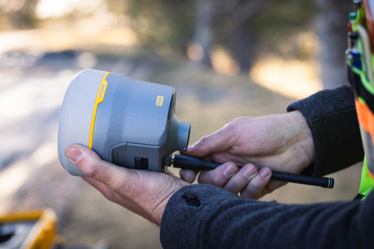 Trimble R980 in a surveyor's hands having the radio antenna attached